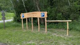 Holzschild mit Aufschrift Fahrradparkplatz vor Waldstück